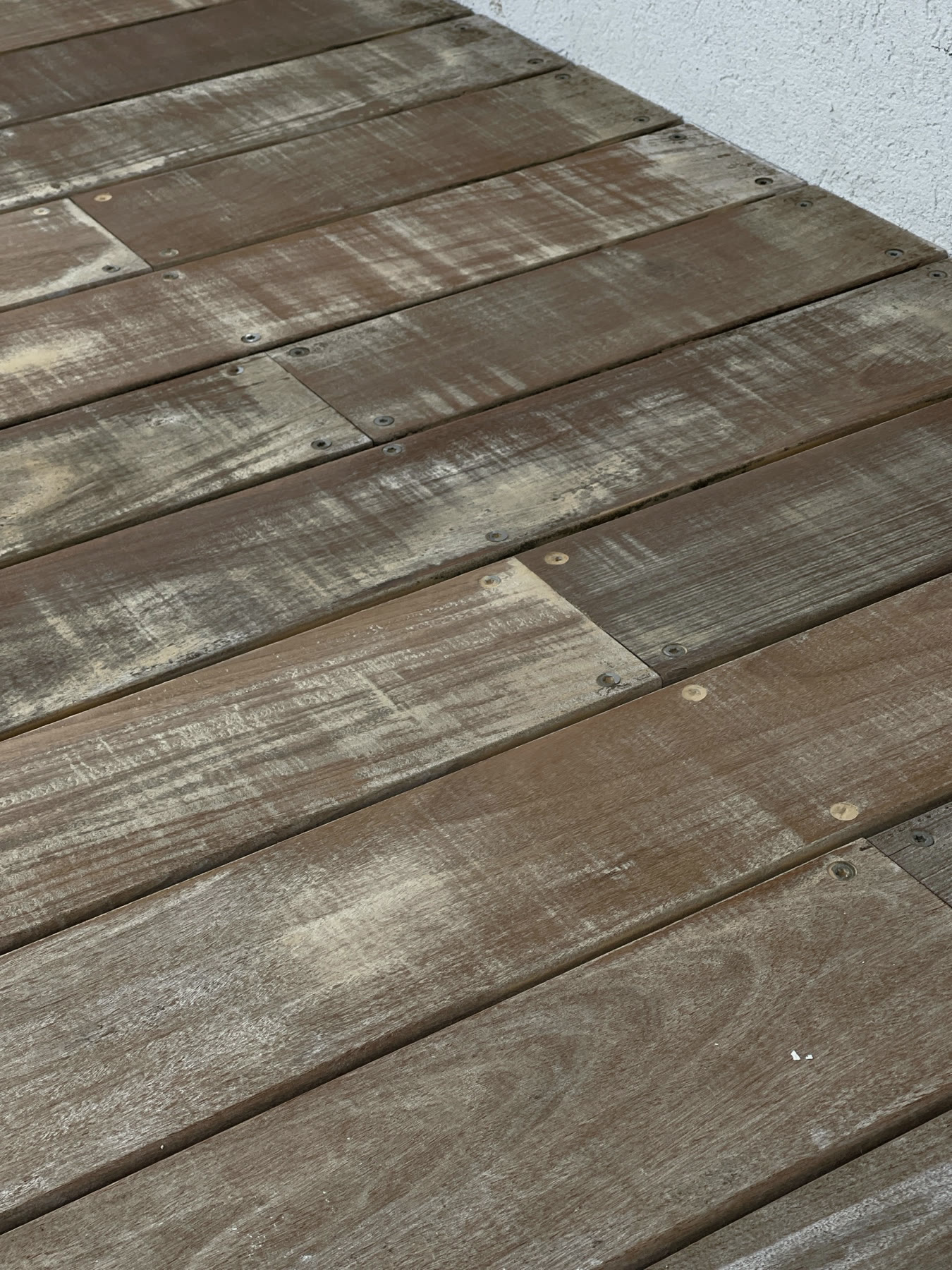 Weathered deck boards before restoration, the grain silvered by sun and salt